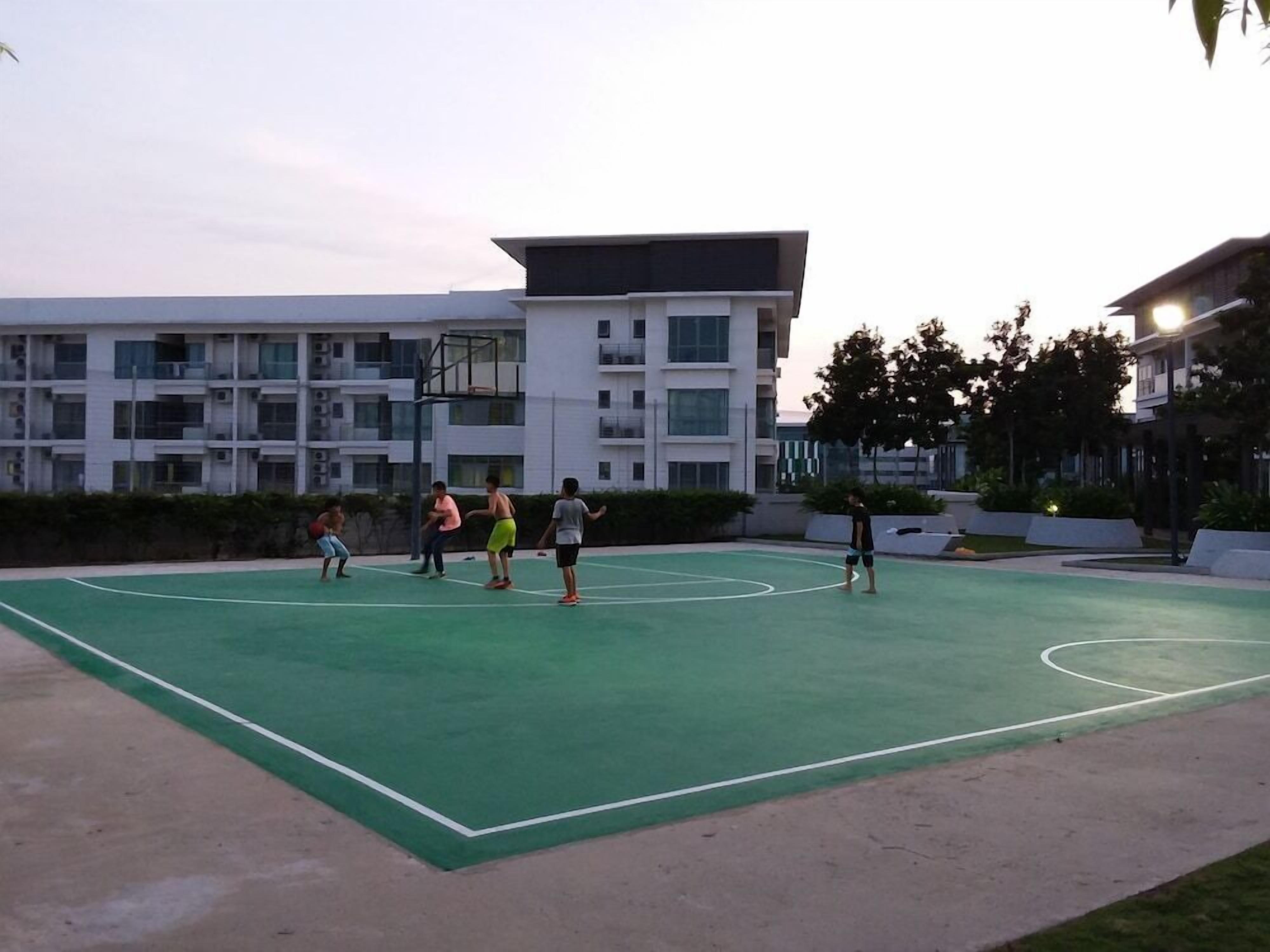 Un terrain de basket en plein air, entouré d’immeubles modernes.