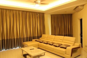 Una sala de estar con un sofá color beige, una mesa de centro y cortinas.