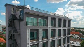 Un hôtel à plusieurs étages, doté d’un design moderne, avec des balcons à chaque étage et un escalier apparent sur le côté gauche.