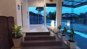 Un intérieur moderne avec un escalier menant à une porte vitrée, des plantes en pot et une vue sur l’extérieur.