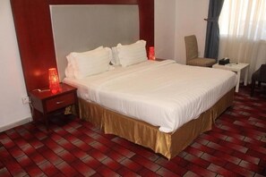 Una habitación de hotel con una cama grande, una mesita de noche, una silla y una pequeña mesa.