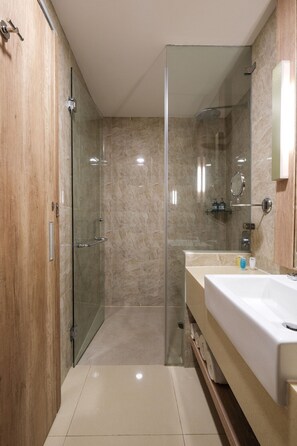 A modern bathroom with a glass shower enclosure, a wooden vanity, and a large mirror. - Bigland Hotel Bogor (Bogor)