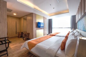 A hotel room with a bed, a TV, a desk, and a view of the city. - Bigland Hotel Bogor (Bogor)