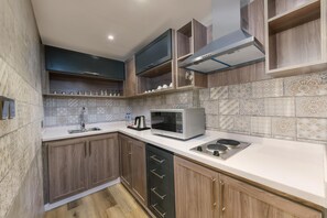 A modern kitchen with wooden cabinets, a built-in microwave, and a stainless steel sink. - Sarwat Park Hotel (Abha)