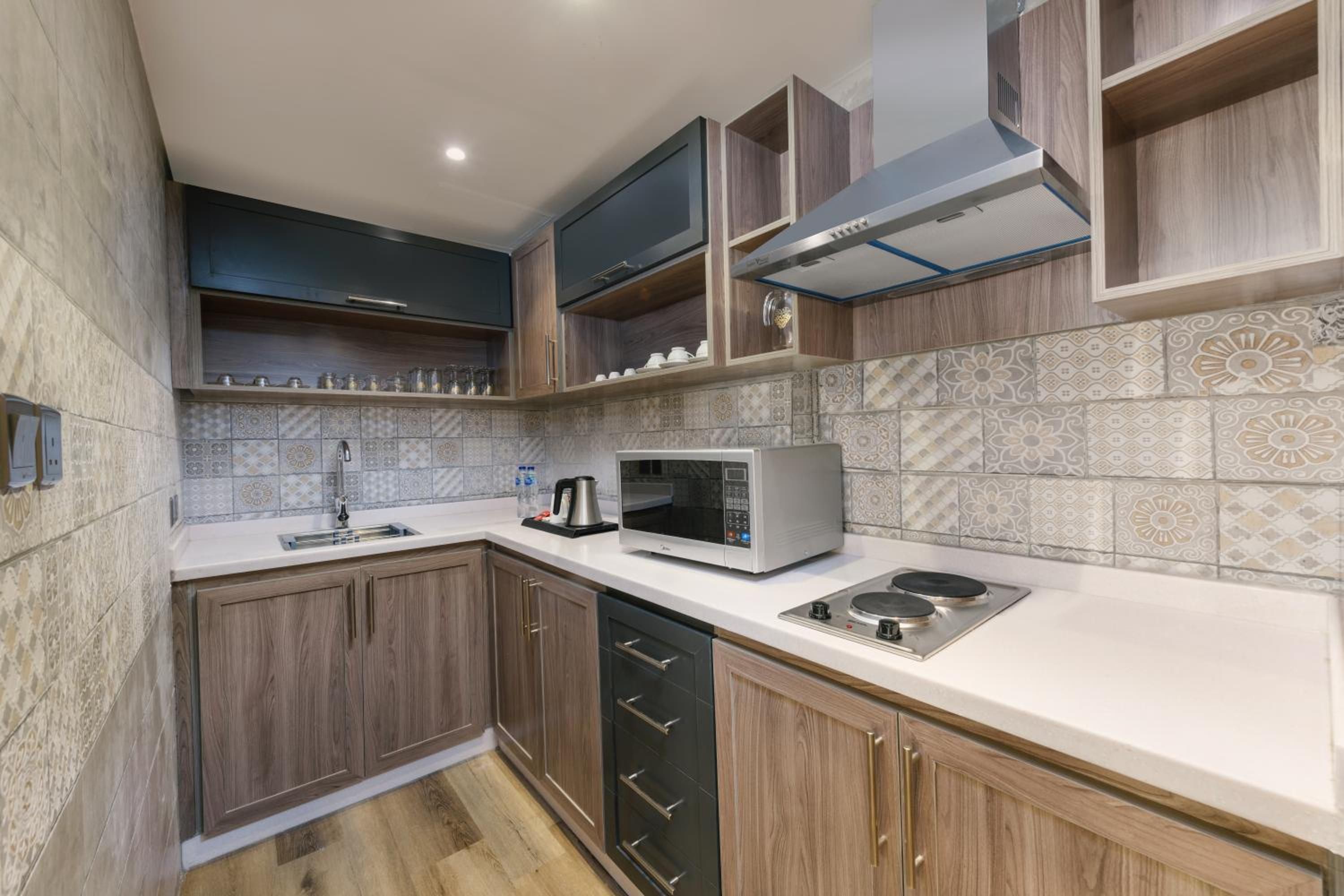 Una cocina moderna con armarios de madera, microondas integrado y pileta de acero inoxidable.