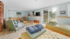Ein gemütliches Wohnzimmer mit einer Couch, einem kleinen Tisch, einem Fernseher und einer Schiebetür, die auf einen Balkon führt.