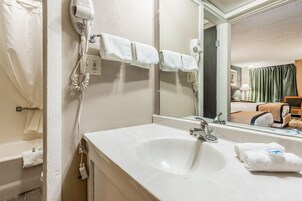 Un baño de hotel con un lavabo blanco, un espejo y dos secadores de pelo montados en la pared.