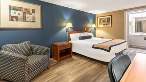 A hotel room with a bed, a chair, a nightstand, and two wall-mounted lamps.