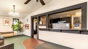 A reception area with a counter, a ceiling fan, a plant, and a wall-mounted sign.