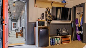 A compact room with a kitchenette, a small refrigerator, a microwave, a shelf with a backpack, and a pair of skis. - THE RED Lodge INN (Red Lodge)