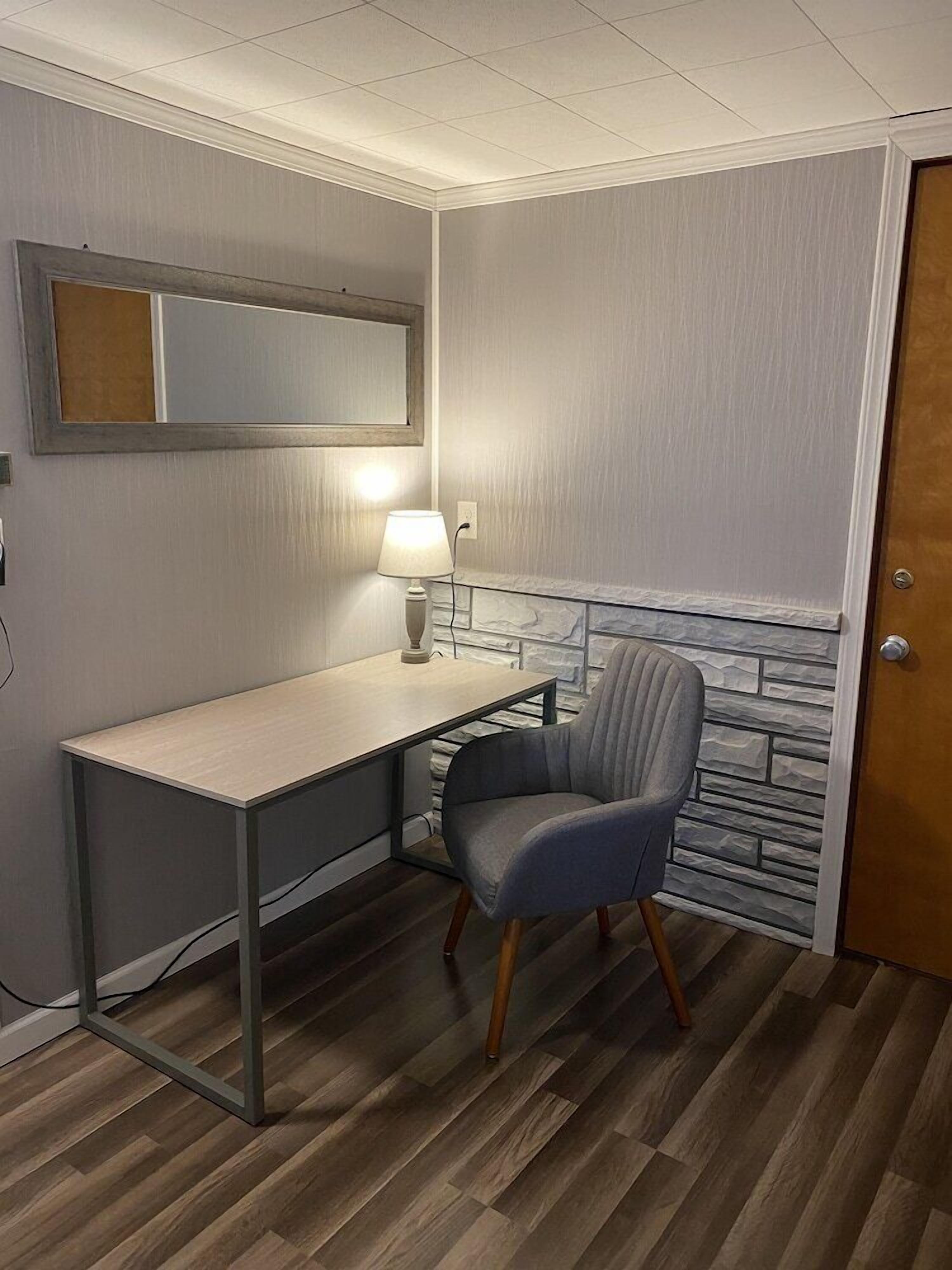 A compact room with a desk, chair, and a lamp.