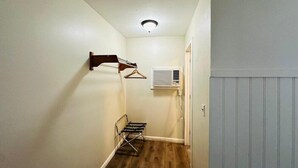 Un pasillo estrecho con suelo de madera, un perchero de pared, un radiador y una puerta.