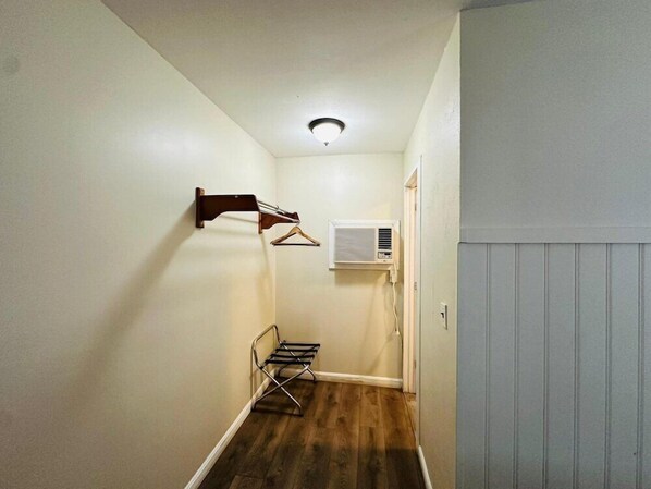 Ein schmaler Korridor mit Holzboden, einer an der Wand befestigten Kleiderstange, einem Heizkörper und einer Tür.