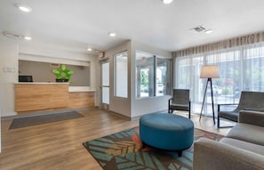 A hotel lobby with a reception desk, seating area, and large windows. - Woodspring Suites Portland North Gresham (Portland)