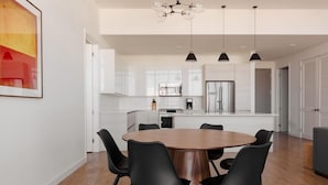 Une cuisine moderne avec des meubles blancs, un îlot central et des luminaires suspendus noirs.