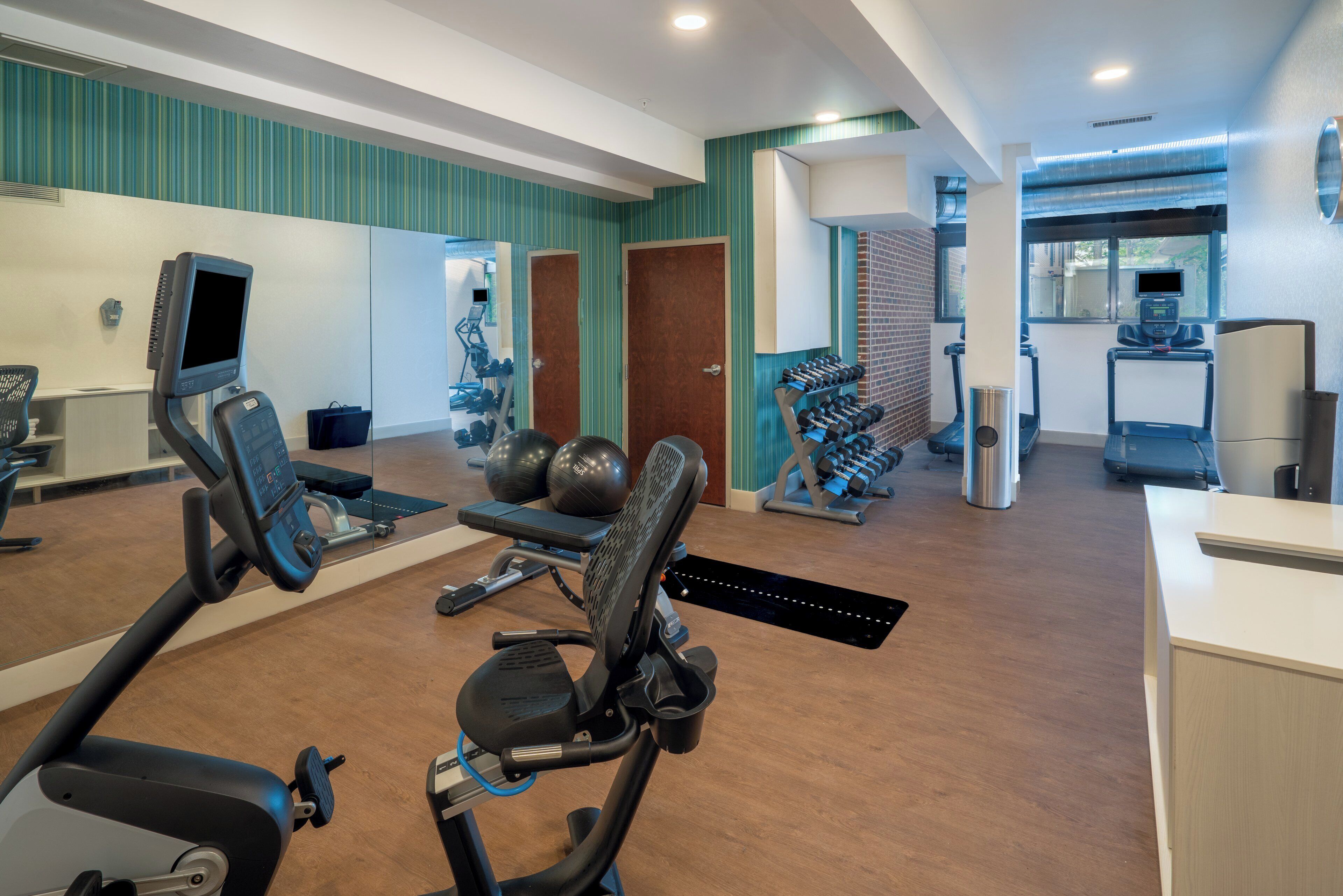 Een fitnessruimte met cardioapparatuur, krachtapparaten en een spiegel.