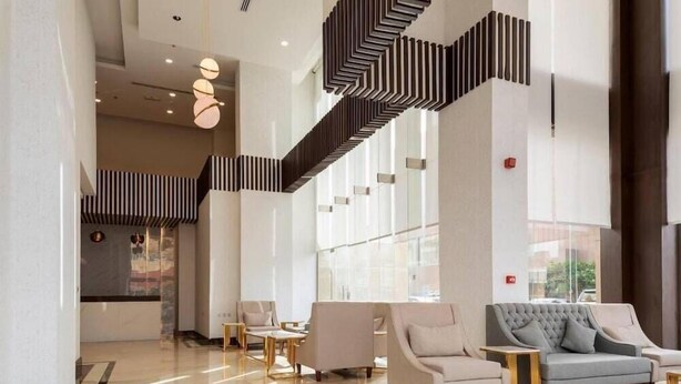 A spacious lobby with a modern staircase, comfortable seating, and large windows. - Seiba Serviced Apartment- Riyadh (Riyadh)