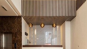 A modern reception area with a marble counter, a vertical striped design on the ceiling, and three pendant lights. - Seiba Serviced Apartment- Riyadh (Riyadh)