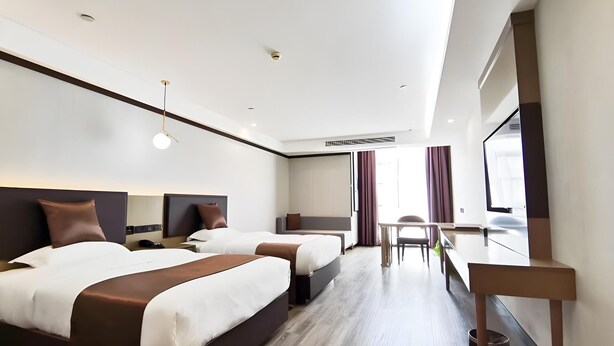Una habitación de hotel moderna con dos camas, un escritorio y un ventanal grande.