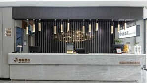 Un mostrador de recepción de hotel con diseño moderno, que incluye un logotipo, un área de recepción y una pantalla digital.