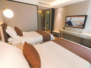 Een hotelkamer met twee bedden, een televisie, een bureau en een spiegel.