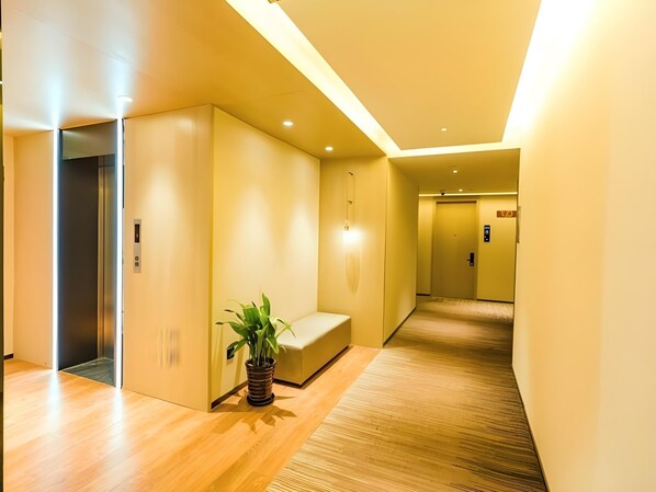 A modern hallway with a wooden floor, a bench, and a potted plant. - GYA Shanghai Jiangpu Hotel (Shanghai)