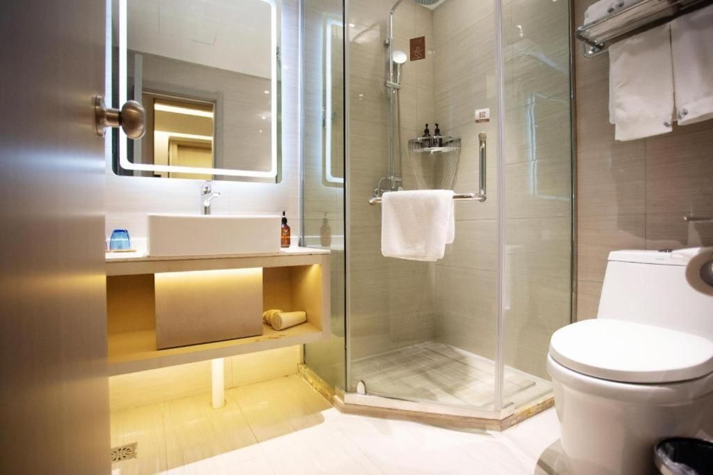 A modern bathroom with a glass-enclosed shower, a white sink, and a toilet.