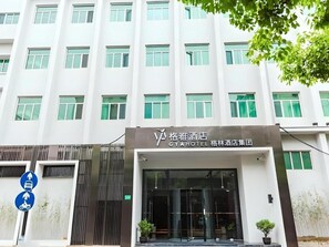 A hotel entrance with a modern facade, large windows, and a sign indicating the hotel name. - GYA Shanghai Jiangpu Hotel (Shanghai)