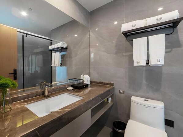 Une salle de bain moderne avec un grand miroir, un lavabo, des toilettes et un porte-serviettes.