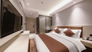 Une chambre d’hôtel moderne avec un grand lit, une table de chevet avec un téléphone, un téléviseur fixé au mur et un placard à portes coulissantes.