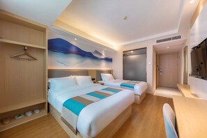 Une chambre d’hôtel avec deux lits, une armoire en bois, un tableau au mur et un bureau avec une chaise.