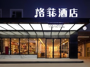 A hotel entrance with a modern design, glass doors, and a sign above the entrance. - VX Xiamen Siming District Huandao Road Hotel (Xiamen)