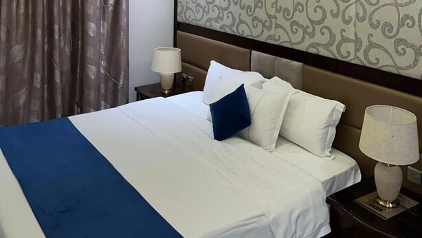 A hotel room with a bed, a nightstand, an air conditioning unit, and a patterned headboard. - Maset Al Masem Al Khobar (Al Khobar)