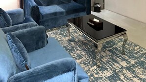 A modern living room with a blue sofa, a coffee table, a flat-screen TV, and a patterned rug. - Maset Al Masem Al Khobar (Al Khobar)
