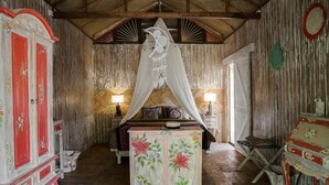 A rustic room with a bed under a canopy, wooden walls, and traditional furniture. - La Luna Resort Yogyakarta (Ngaglik)