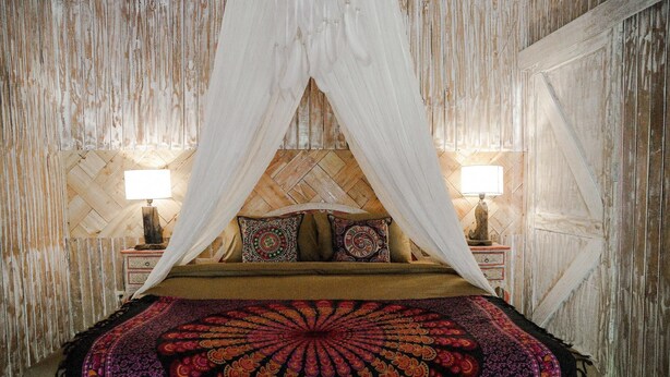 A bed with a canopy, patterned pillows, and two bedside lamps. - La Luna Resort Yogyakarta (Ngaglik)