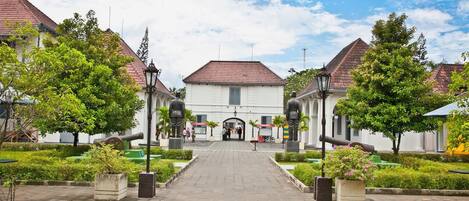 A courtyard with a central pathway leading to a building with a red-tiled roof.