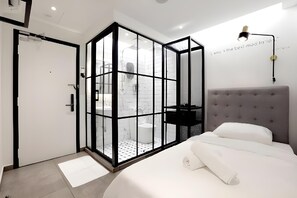 A modern bedroom with a bed, a bedside lamp, and a glass partition separating the room. - Z Hotel Ara Damansara, Lrt, Mall, Airport (Petaling Jaya)