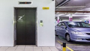 Een lift met een hotel logo, een auto in een parkeergarage en een brandblusser.