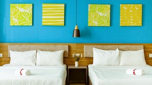 Une chambre d’hôtel avec deux lits, un mur bleu et trois œuvres d’art.