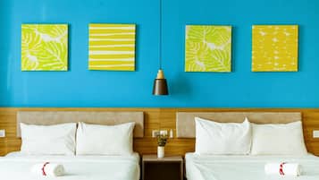 A hotel room with two beds, a blue wall, and three artwork pieces.