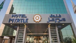 A modern hotel with a prominent glass facade, a staircase leading to the entrance, and bilingual signage. - Elian Hotel (Riyadh)