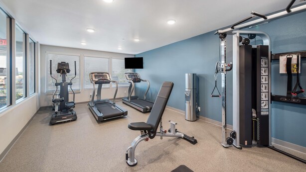 A gym with treadmills, a stationary bike, and a weight bench. - Woodspring Suites Orlando Kissimmee Maingate (Kissimmee)
