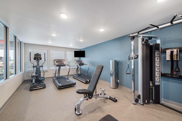 A gym with treadmills, a stationary bike, and a weight bench. - Woodspring Suites Orlando Kissimmee Maingate (Kissimmee)