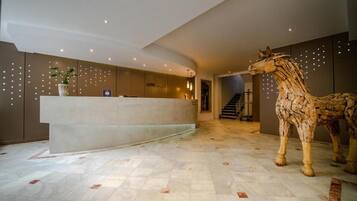 A reception area with a reception desk, a potted plant, and a large horse sculpture.