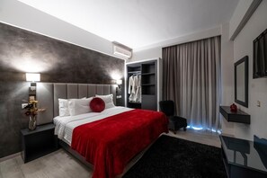 Una camera d'hotel moderna con un letto grande, un comodino, un armadio e uno specchio.
