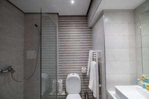 A modern bathroom with a glass shower enclosure, a toilet, and a sink. - Lingos Hotel (Florina)