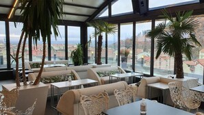 A restaurant with indoor seating, large windows, and potted plants.