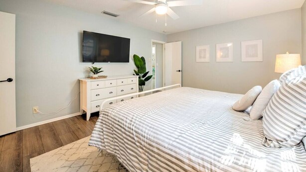 A bedroom with a bed, a dresser, a TV, and a ceiling fan. - Ultimate Tiki Retreat - 10 Min to Beach! (Bradenton)