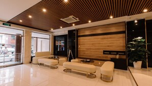 A modern lobby with a wooden ceiling, a reception desk, and a seating area with sofas and a bench. - Chotel Ben Thanh (Ho Chi Minh City)